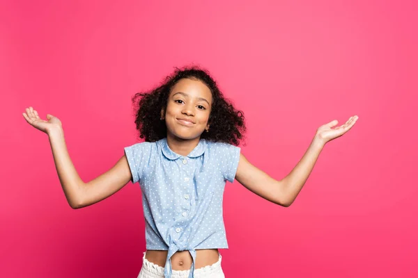 Sorridente carino riccio africano americano bambino mostrando gesto scrollata di spalle isolato su rosa — Foto stock