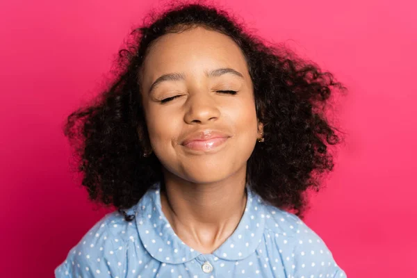 Complacido lindo rizado africano americano niño con los ojos cerrados aislado en rosa - foto de stock