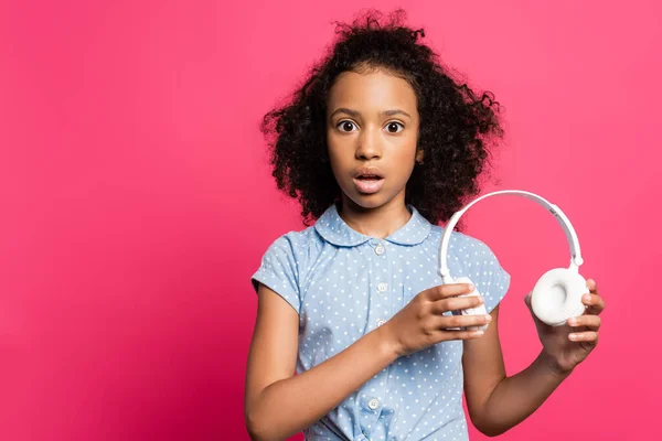 Shocked cute curly african american kid with headphones isolated on pink — Stock Photo