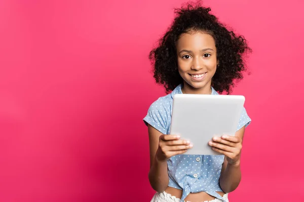 Sourire mignon frisé afro-américain enfant en utilisant une tablette numérique isolé sur rose — Photo de stock