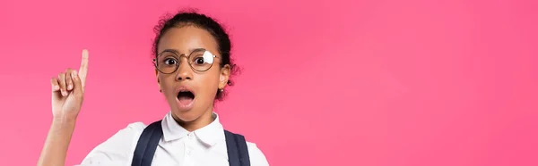 Shocked african american schoolgirl in glasses showing idea gesture isolated on pink, panoramic shot — Stock Photo