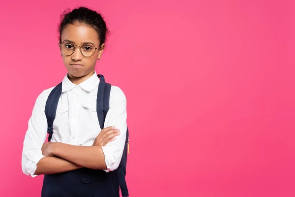 Beleidigt afrikanisch-amerikanische Schülerin in Brille mit Rucksack und verschränkten Armen isoliert auf rosa — Stockfoto