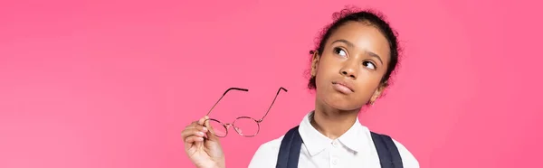 Pensativa afroamericana colegiala con gafas aisladas en rosa, tiro panorámico - foto de stock