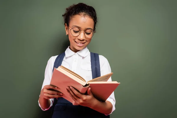 Sorridente Africano americano estudante leitura livro perto vazio verde quadro — Fotografia de Stock