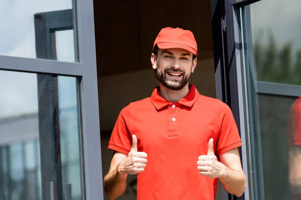 Handsome waiter in uniform showing thumbs up near cafe on urban street — Stock Photo