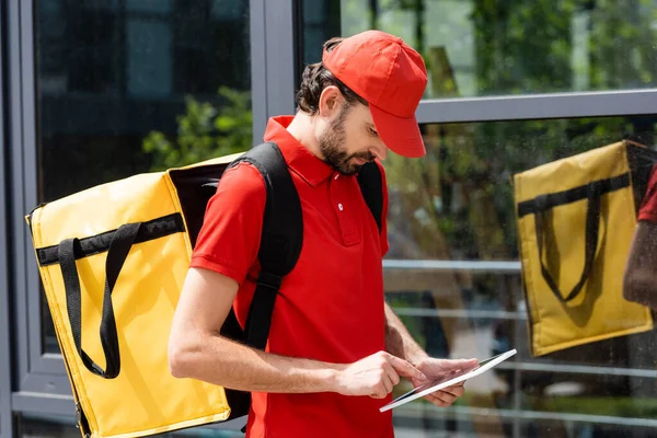 Courier with thermo backpack using digital tablet on urban street — Stock Photo