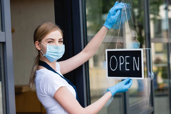 Waitress hanging signboard with open word at entry of cafe — Stock Photo
