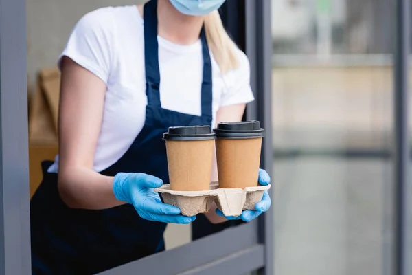 Ausgeschnittene Ansicht der Kellnerin, die Pappbecher in der Nähe des Cafés hält — Stockfoto