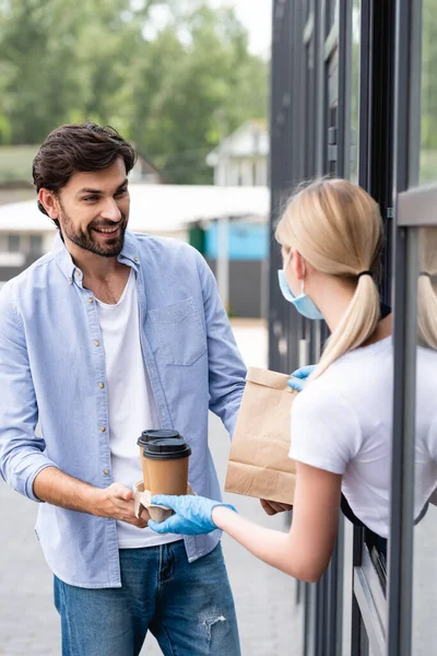 Focus selettivo dell'uomo che sorride e guarda la cameriera mentre riceve l'ordine vicino alla caffetteria — Foto stock