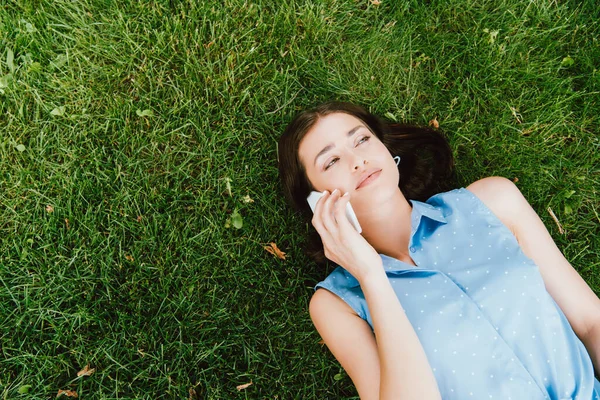Vista superior da menina deitada na grama verde e falando no smartphone — Fotografia de Stock