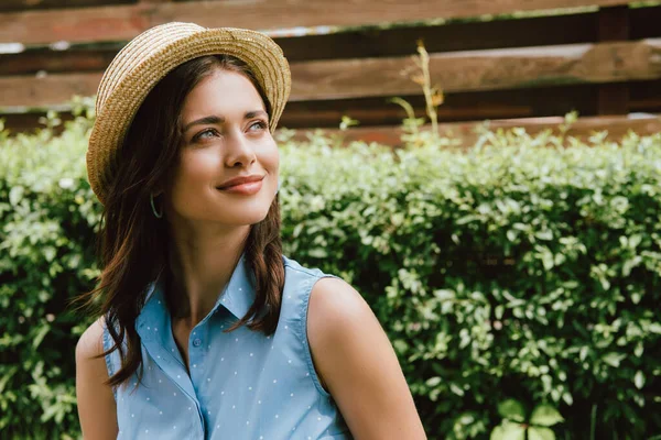 Щаслива молода жінка в солом'яному капелюсі дивиться назовні — стокове фото
