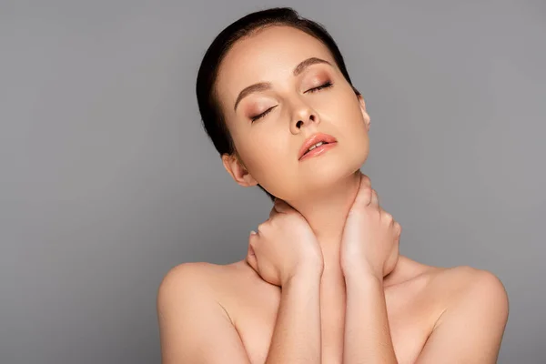 Beautiful naked woman with perfect skin and closed eyes touching neck isolated on grey — Stock Photo