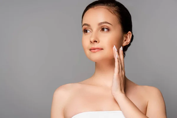 Belle femme avec peau parfaite toucher le visage et regarder loin isolé sur gris — Photo de stock