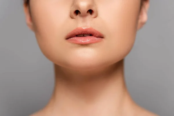 Vista recortada de labios brillantes femeninos aislados en gris - foto de stock