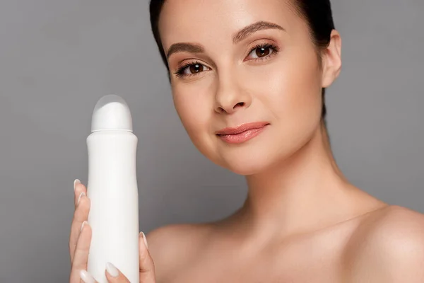 Naked beautiful brunette woman holding deodorant isolated on grey — Stock Photo