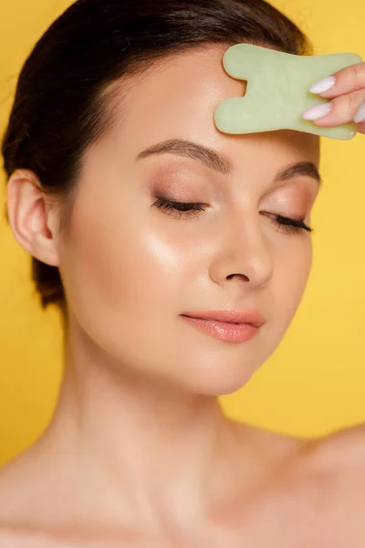 Portrait of beautiful naked woman facial jade gua sha isolated on yellow — Stock Photo