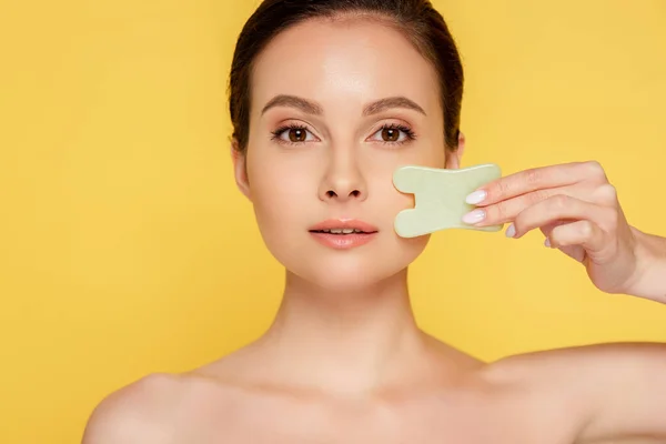 Beautiful naked woman facial jade gua sha isolated on yellow — Stock Photo