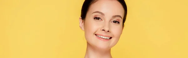 Smiling beautiful brunette woman with perfect skin isolated on yellow, panoramic shot — Stock Photo