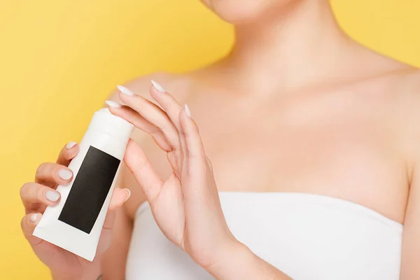 Cropped view of woman holding hand cream isolated on yellow — Stock Photo