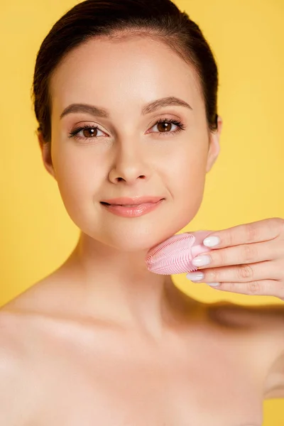 Hermosa mujer desnuda usando cepillo de limpieza facial aislado en amarillo — Stock Photo