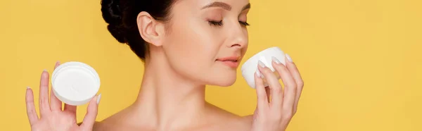 Beautiful naked woman smelling cosmetic cream isolated on yellow, panoramic shot — Stock Photo