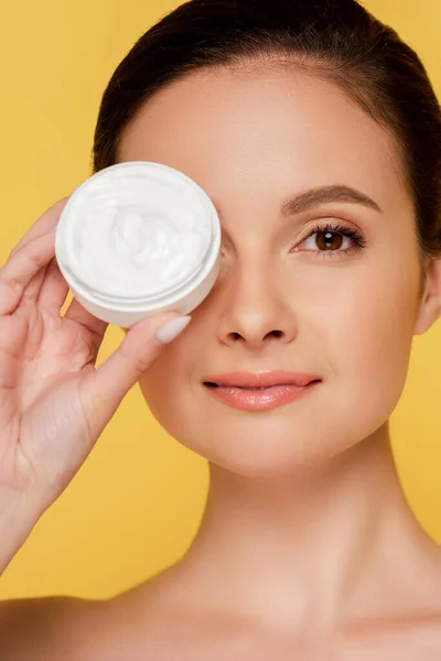 Portrait of beautiful naked woman holding container with cosmetic cream isolated on yellow — Stock Photo