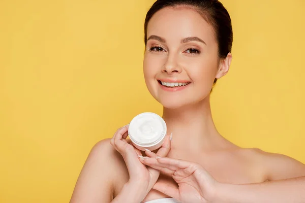 Smiling beautiful naked woman holding container with cosmetic cream isolated on yellow — Stock Photo