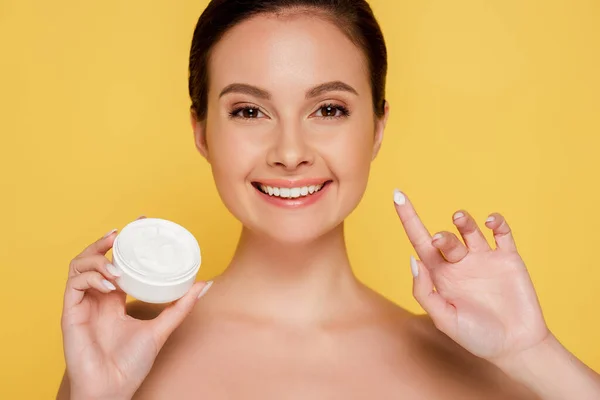 Smiling naked beautiful woman with cosmetic cream on finger isolated on yellow — Stock Photo