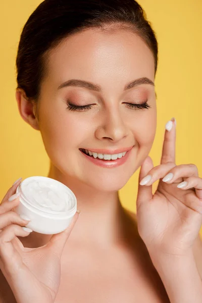 Smiling naked beautiful woman with cosmetic cream on finger isolated on yellow — Stock Photo
