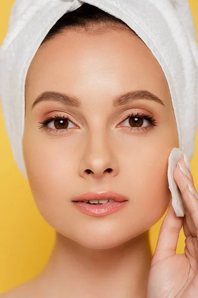 Belle femme avec serviette sur la tête en utilisant un tampon de coton isolé sur jaune — Photo de stock