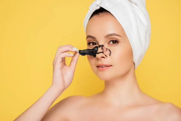 Beautiful naked woman with towel on head removing blackheads on nose isolated on yellow — Stock Photo