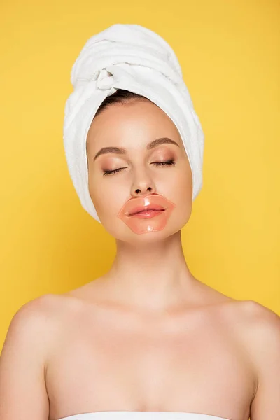 Belle femme avec serviette sur la tête, patch lèvres et les yeux fermés isolés sur jaune — Photo de stock