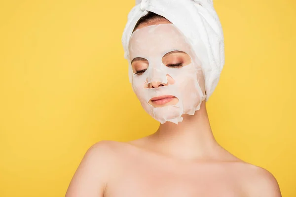 Nackte schöne Frau mit Handtuch auf dem Kopf und Gesichtsmaske isoliert auf gelb — Stockfoto