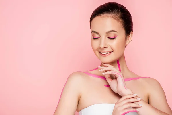 Smiling beautiful woman with pink lines on body isolated on pink — Stock Photo