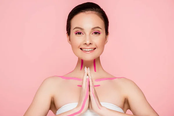 Lächelnd schöne Frau mit rosa Linien auf dem Körper zeigt bitte Geste isoliert auf rosa — Stockfoto
