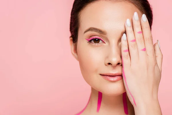 Beautiful woman with pink lines on body covering face with hand isolated on pink — Stock Photo