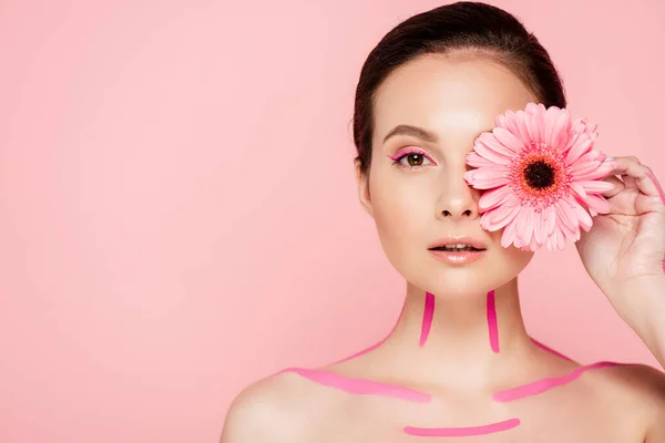 Nudo bella donna con linee rosa sul corpo e crisantemo vicino occhio isolato su rosa — Foto stock