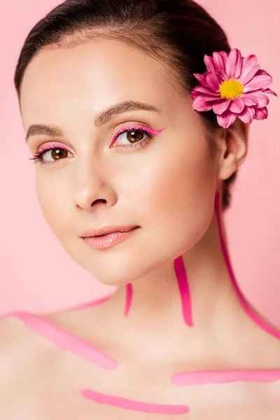 Bella donna nuda con linee rosa sul corpo e fiore nei capelli isolati su rosa — Foto stock