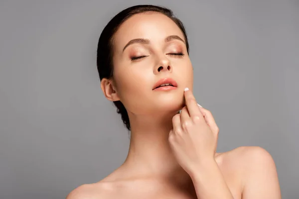 Beautiful naked woman with perfect skin and closed eyes touching face isolated on grey — Stock Photo