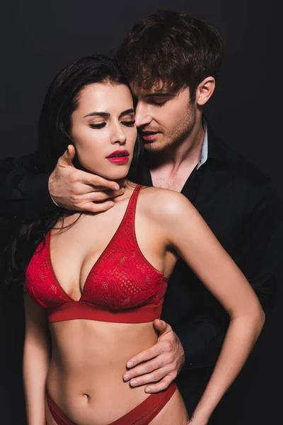 Passionné homme toucher sexy copine en rouge sous-vêtements isolé sur noir — Photo de stock