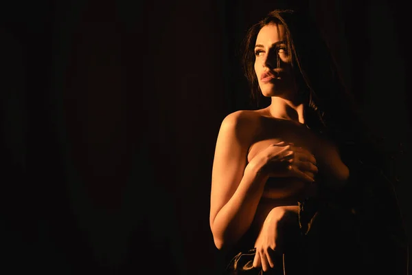 Illuminazione sulla donna attraente avvolto in lenzuolo di seta che copre il seno isolato su nero — Foto stock