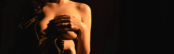 Cultivo panorámico de mujer sensual envuelto en sábana de seda que cubre el pecho aislado en negro - foto de stock