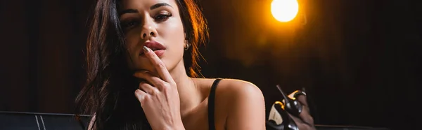 Colpo panoramico di donna sexy sdraiata e toccante labbra su nero — Foto stock