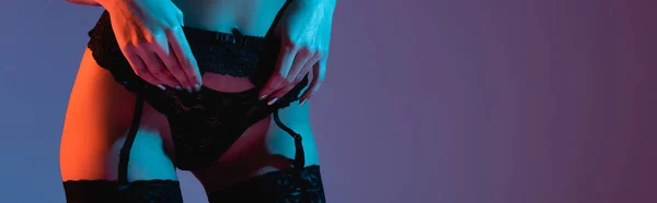 Горизонтальний урожай сексуальної молодої жінки торкається трусиків ізольовані на фіолетовому — стокове фото