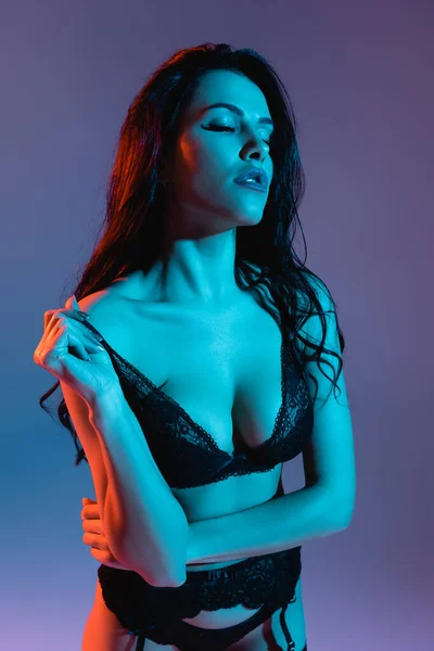 Сексуальна молода жінка торкається бюстгальтера ізольовано на фіолетовому — стокове фото