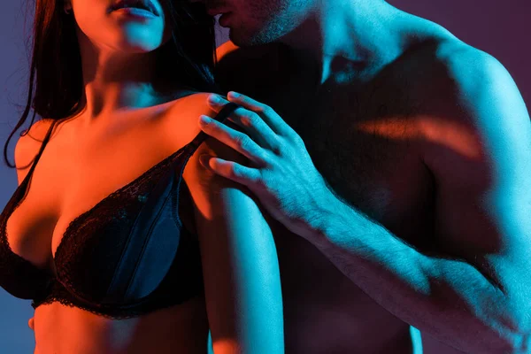 Обрізаний вид без сорочки чоловік торкається бюстгальтера сексуальної жінки на фіолетовому — стокове фото