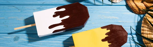 Vista superior de conchas e folhas de palma perto de sorvete em fundo azul de madeira, tiro panorâmico — Fotografia de Stock