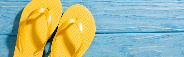 Top view of yellow flip flops on wooden blue background, panoramic shot — Stock Photo