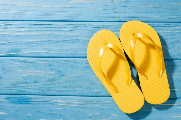 Top view of yellow flip flops on wooden blue background — Stock Photo