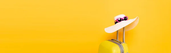 Sun hat and sunglasses on suitcase handle on yellow background, panoramic shot — Stock Photo